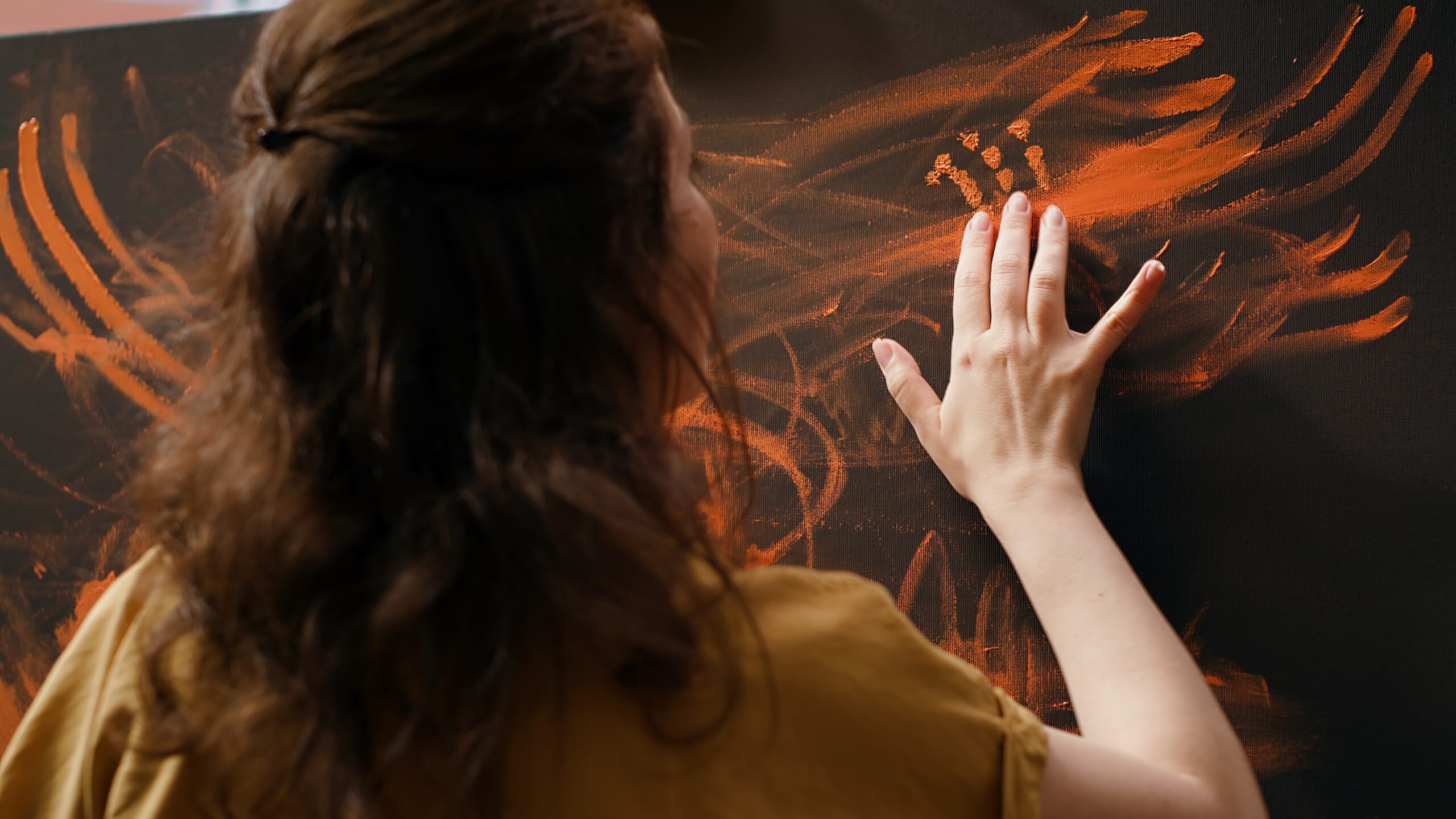 Confident artist stands before an easel and painting with her fingers, innovative finger paint and handprint technique for creating a beautiful artwork with watercolor paints. Rustic art. Camera A.